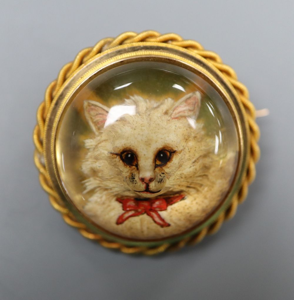 A Victorian yellow metal and Essex crystal set circular brooch, decorated with the head of a cat, with ropetwist border,